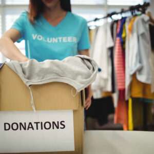female-volunteer-holding-clothes-in-donation-box